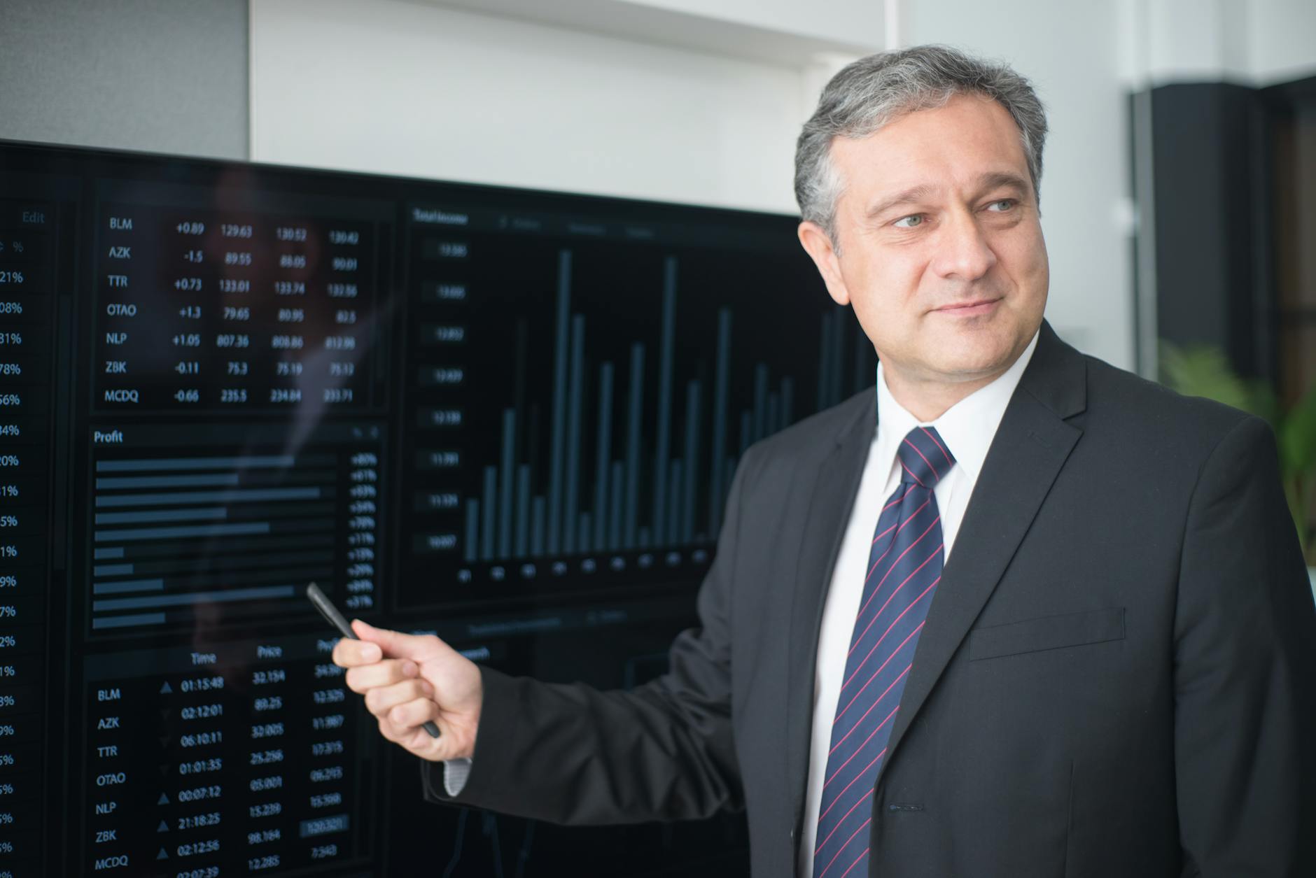 man wearing a black suit holding a pen